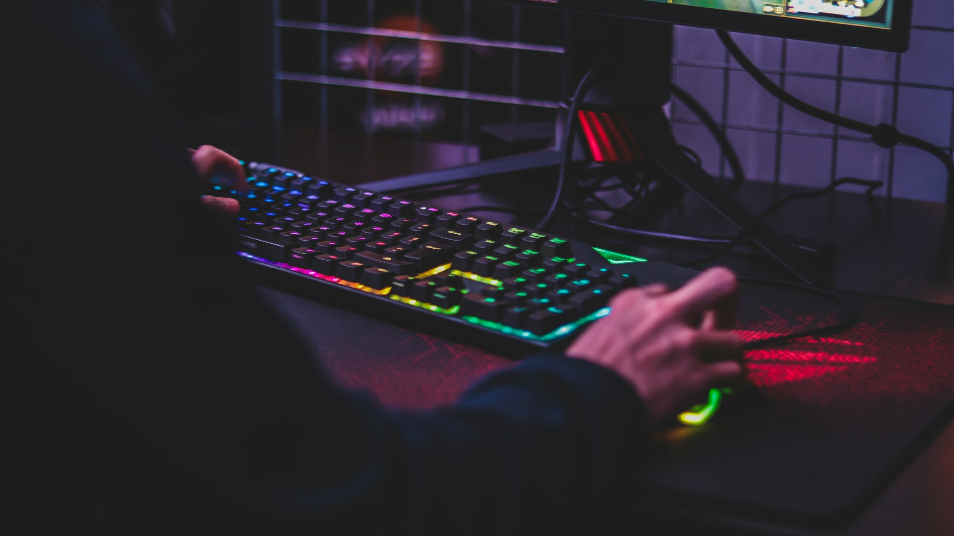 Neon-lit gaming battlestation with mechanical keyboard and monitors